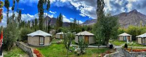 a group of tents in a field with mountains in the background at Mystique meadows earth homes in Hundar