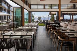 ワイレアにあるAC Hotel by Marriott Maui Waileaのテーブルと椅子と窓のあるレストラン