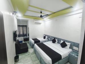 Un dormitorio con dos camas y una silla dentro. en Hotel the stay lions, en Ahmedabad