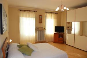 a bedroom with a white bed and a television at Cascina Fietta - Wine Dreams Apartments in Pontestura