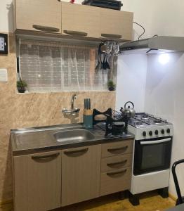 a small kitchen with a stove and a sink at cabaña NFF in Punta Del Diablo