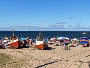 people on a beach with boats on the sand at cabaña NFF in Punta Del Diablo