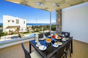 a dining room with a table and chairs and a balcony at Aroma Villas in Hersonissos