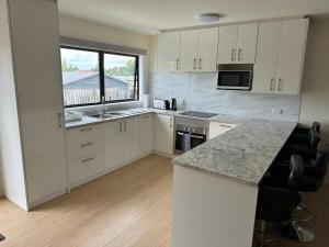 a kitchen with white cabinets and a large window at The White House Apartment in Tokoroa