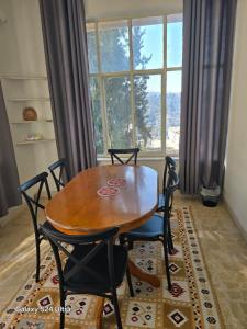 een eettafel en stoelen voor een raam bij Lukanda Apartment Feel at Home in Amman