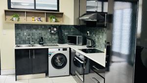 a kitchen with a washing machine and a sink at C&J Luxe Apartments in Windhoek