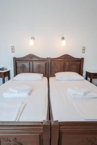 two beds with white sheets and wooden headboards at Evgatis Hotel in Kondiás