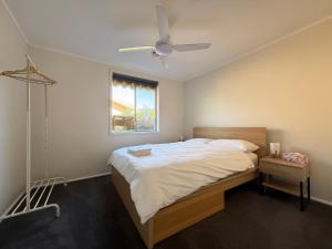 キャンベラにあるPage 3BR Houseのベッドと天井扇風機のある寝室