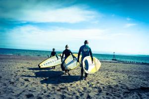 three men standing on the beach with their surfboards at Exmouth Country Lodge and Cottage in Exmouth