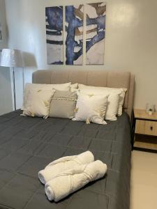 a bed with white pillows and a blanket on it at Cozy and Affordable Deluxe Condo near Puerto Princessa Airport in Puerto Princesa City