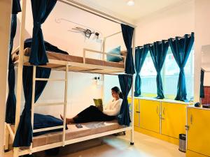 a woman sitting on a bunk bed in a room at GreenDay Escapes Rishikesh in Rishīkesh