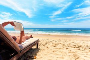 a woman laying on a beach reading a book at Kya Venice and Beach House: Venezia, mare e laguna in Cavallino-Treporti