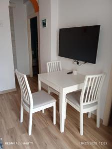 a white dining room table with two chairs and a flat screen tv at Casa Tropical in Salobreña