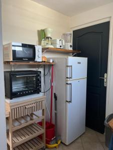 a kitchen with a microwave and a refrigerator at LA PAILLOTE D OR in Sainte-Anne