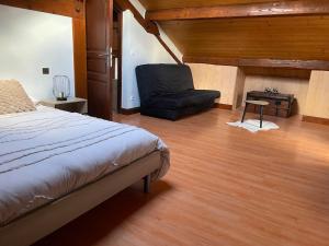 a bedroom with a bed and a chair at Le Nid des Bois - Maison familiale au calme entre forêt et rivière in Albertville