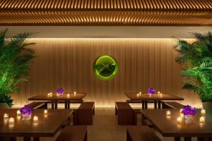 a restaurant with tables and a green clock on the wall at The Tokyo EDITION, Toranomon in Tokyo