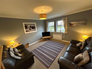 a living room with a leather couch and a television at Brada View Bamburgh in Bamburgh