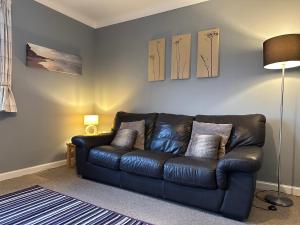 a black leather couch sitting in a living room at Brada View Bamburgh in Bamburgh
