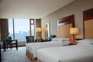 um quarto de hotel com duas camas, uma mesa e cadeiras em Renaissance Wuhan Hotel em Wuhan