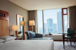 um quarto de hotel com uma cama e uma janela grande em Renaissance Wuhan Hotel em Wuhan