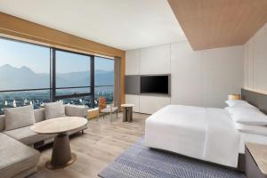P'u-yang-chenにあるSheraton Pujiangのベッドルーム(ベッド1台、ソファ、テレビ付)