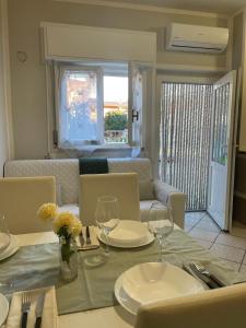 a dining room table with glasses and a couch at Bnbook Lago Magico in Dormelletto