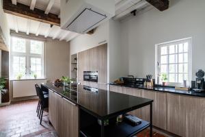 a kitchen with a large black island in a room at Beddermolen - Molenhuis op historisch erfgoeddomein in Westerlo