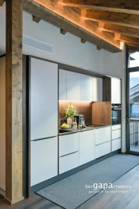 een keuken met witte kasten en een houten plafond bij BergVibes in Garmisch-Partenkirchen +44 foto's