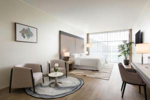 a hotel room with a bed and a table and chairs at Sheraton Milan Malpensa Airport Hotel & Conference Centre in Ferno