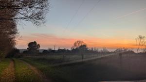 a foggy field with a fence and a sunset at Keeper’s Cottage in Montacute +11 photos
