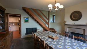 a dining room with a table and a staircase at Keeper’s Cottage in Montacute