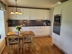 a kitchen with white cabinets and a wooden table with chairs at Irenegarden - Panorama apartment in Lauvstad