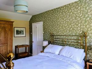 a bedroom with a bed and a green wall at Keeper’s Cottage in Montacute