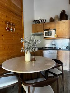 a kitchen with a table with chairs and a vase with flowers at Maison MAEL in Notre-Dame-de-Bellecombe