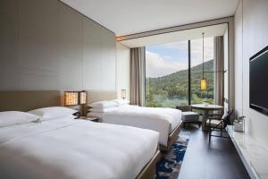 a hotel room with three beds and a large window at Renaissance Taipei Shihlin Hotel in Taipei +42 photos