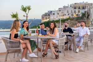 a group of people sitting at tables on a patio at Hotel Punta San Francesco in Vieste