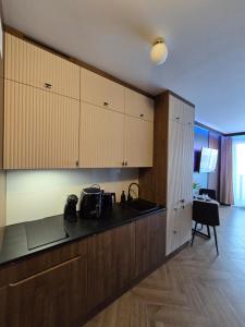 Una cocina con gabinetes de madera y una encimera negra. en Motlava Romantic Loft - Jacuzzi, en Gdansk