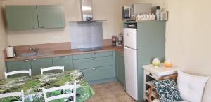 a kitchen with blue cabinets and a white refrigerator at Le Petit Suc in Centrès