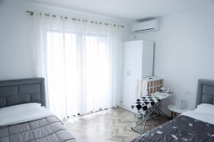 a white bedroom with a bed and a window at Family apartment in Tirana