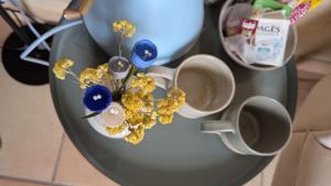 a vase with flowers and two cups on a table at Aux coeurs du Méjean in Mas Saint-Chély
