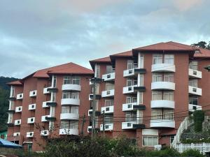 a large red brick building with white balconies at Mountain Breeze Chill Apartment in Nuwara Eliya
