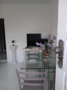 a glass table with a computer monitor and flowers on it at casa OLINDA in Salvador