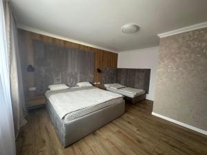 a bedroom with two beds and wooden floors at Country house Egomer in Călugări