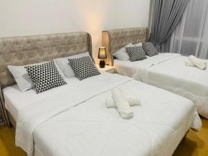 two beds with white sheets and pillows in a room at FUMY Homestay in Kuantan