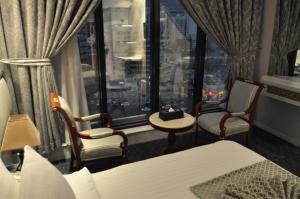 Habitación con cama, 2 sillas y ventana en Montana Al Azizia Hotel, en La Meca