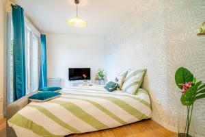 a bedroom with a bed and a tv on a wall at Tropical nest - Taverny - Ligne H in Taverny