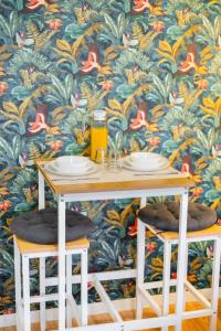 a table with two stools in front of a wallpaper at Le Cosy Nest - Studio à Taverny - Ligne H in Taverny