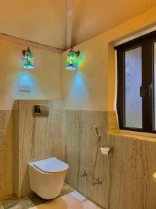 a bathroom with a toilet and stained glass windows at Shivgarh Sustainable Resort in Dādu +28 photos