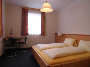 a bedroom with a bed and a table and a window at Lärchenhof in Flachau +20 photos