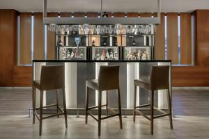 a bar with three chairs and a counter with glasses at AC Hotel Sevilla Fórum by Marriott in Seville